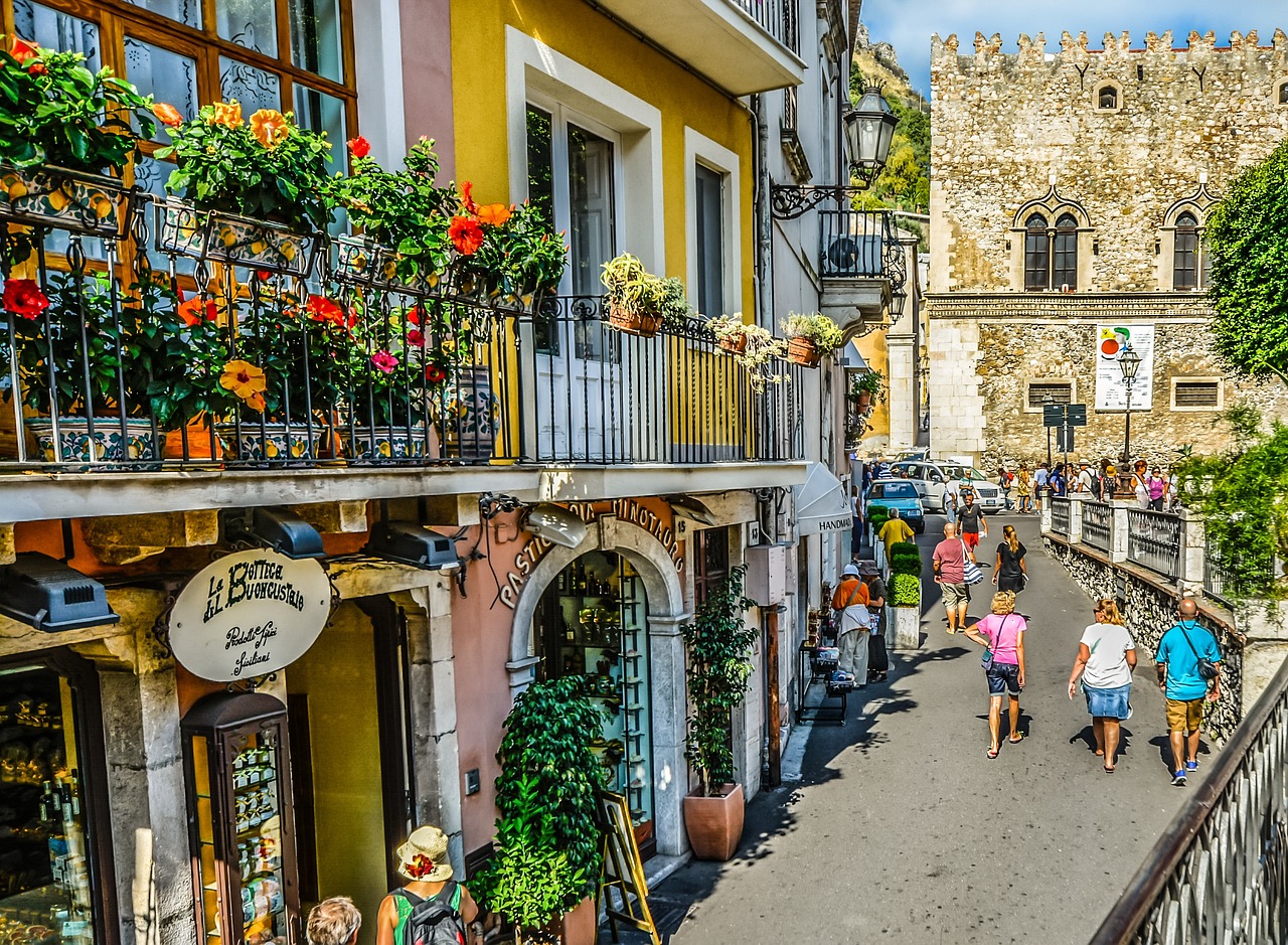 Piazza di Taormina affollata di turisti che gustano gelato artigianale in estate.