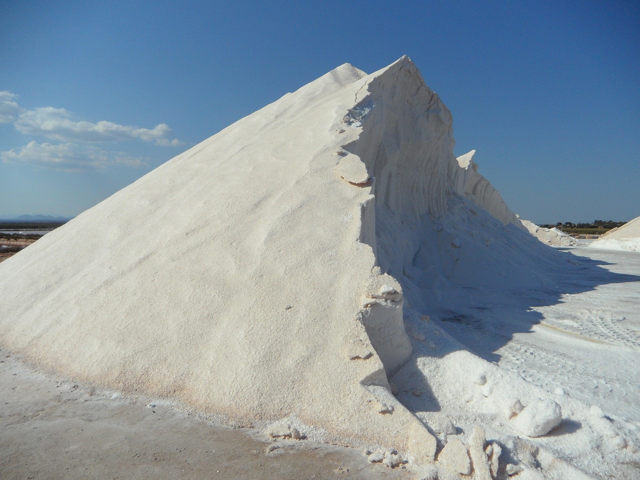 Salinari al lavoro sotto il sole a Trapani, mentre raccolgono il sale marino nelle saline.