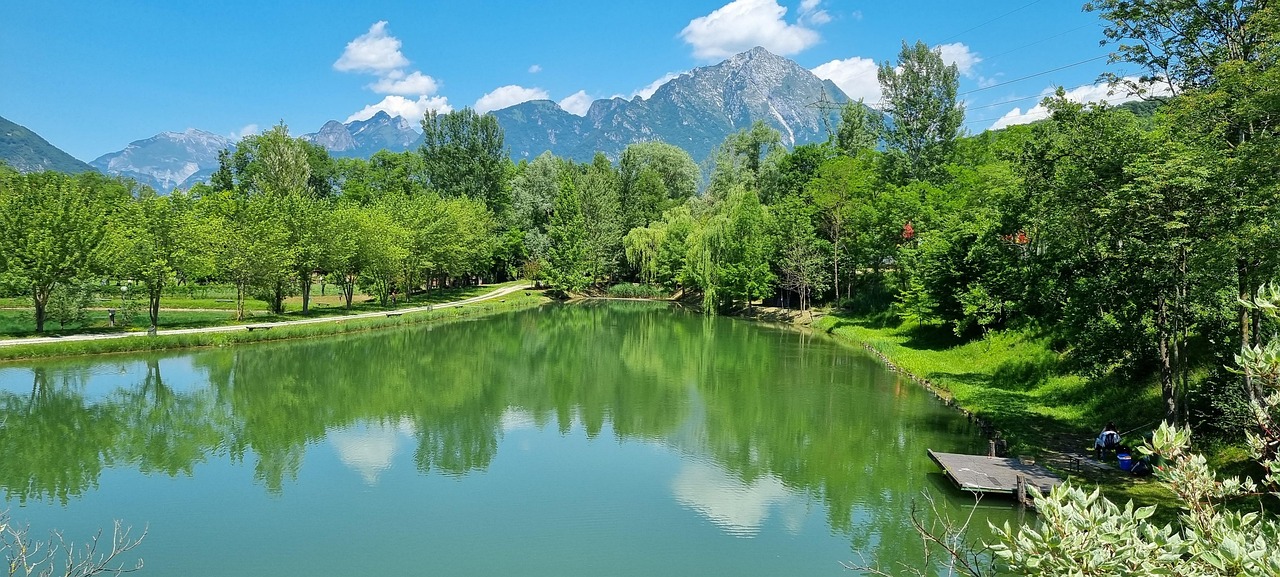 Lago in Trentino circondato da montagne, con acque cristalline e vegetazione lussureggiante.