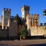 Castello di Sirmione, rocca affacciata sul Lago di Garda, circondata da acque blu e natura.