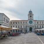 Vista della piazza napoletana con venditori di pizza fritta e turisti che degustano il piatto tipico.
