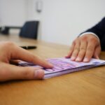 Immagine di un pacchista di "Affari Tuoi" con un sorriso, mentre tiene in mano una busta con un premio sorprendente.