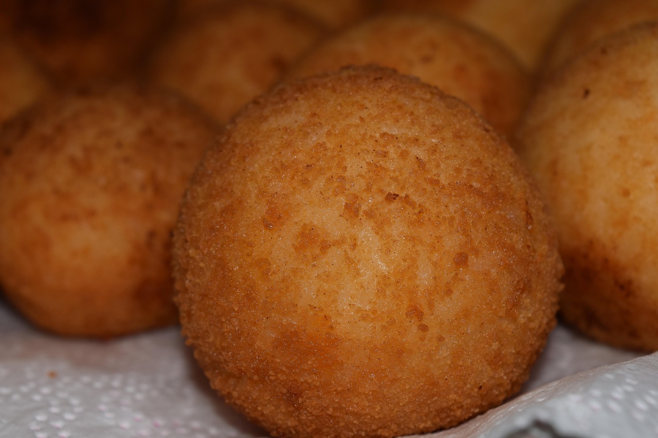 Mercato di Palermo con bancarelle di arancine fresche e colorate, simbolo della tradizione culinaria siciliana.