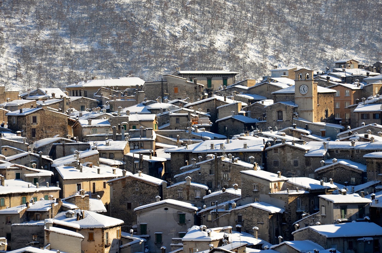 Vista panoramica del borgo incantevole, coperto di neve, con case colorate e luci calde in inverno.