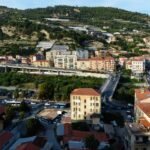 Vista panoramica del comune ligure con cartelli di agevolazioni fiscali per nuovi imprenditori.