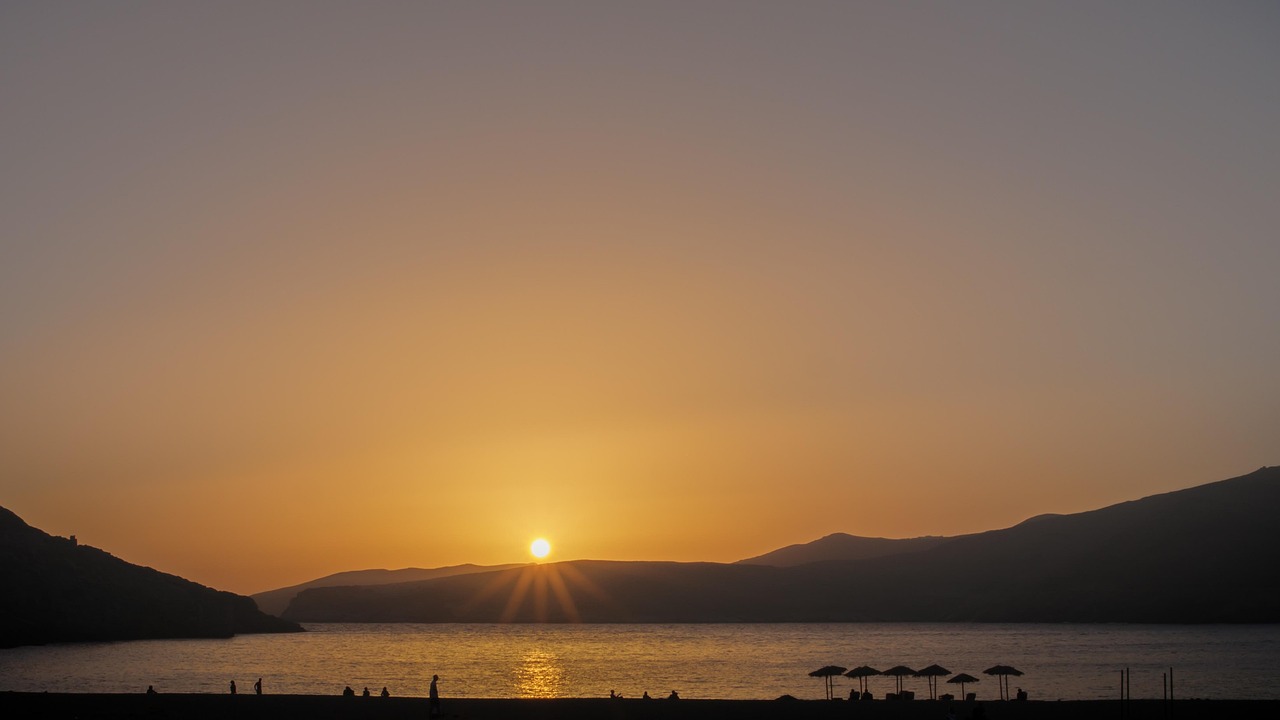 Spiaggia greca con acqua cristallina e romantico tramonto sul mare.