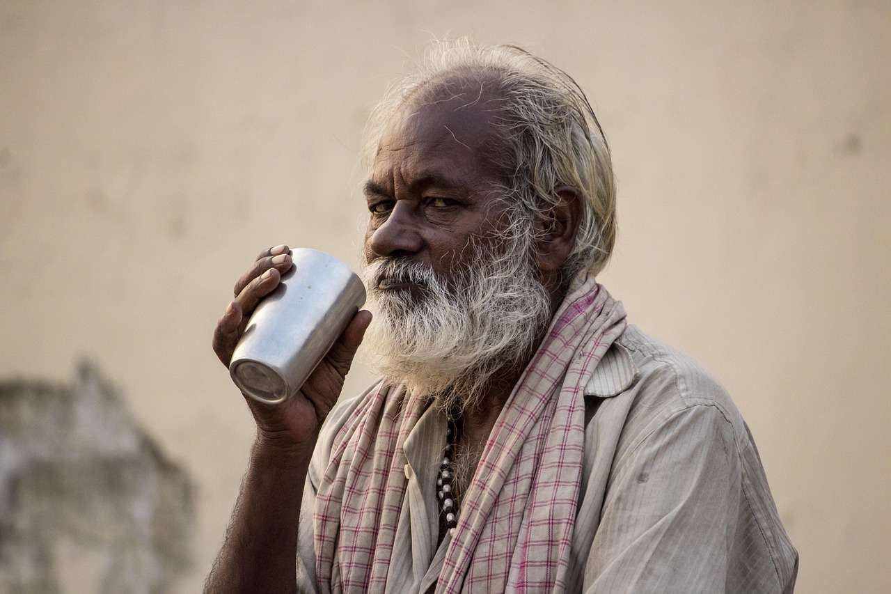 Donna che beve un bicchiere d'acqua calda al mattino, sorridente e concentrata sulla sua routine salutare.