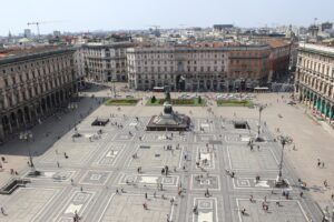 Piazza di Milano affollata, con persone che gustano aperitivi in un'atmosfera vivace e colorata.