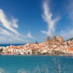 Vista panoramica del suggestivo paese costiero, affollato di turisti e incorniciato da un mare blu cristallino.