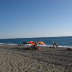 Spiaggia calabrese con sabbia bianca e acque cristalline, ideale per una visita estiva.