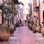 Vicolo di un borgo antico, con facciate colorate e dettagli storici, evocando storie del passato.