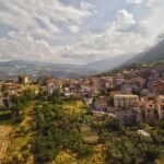 Panorama di un suggestivo paese dell'Abruzzo, con case in pietra e colline verdi sullo sfondo.