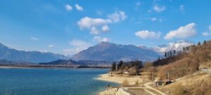 Vista panoramica del lago sottovalutato d'Italia, circondato da montagne e vegetazione lussureggiante.